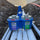 Two cans of Oatey paint and cement in a blue holder against a background of soil and concrete.