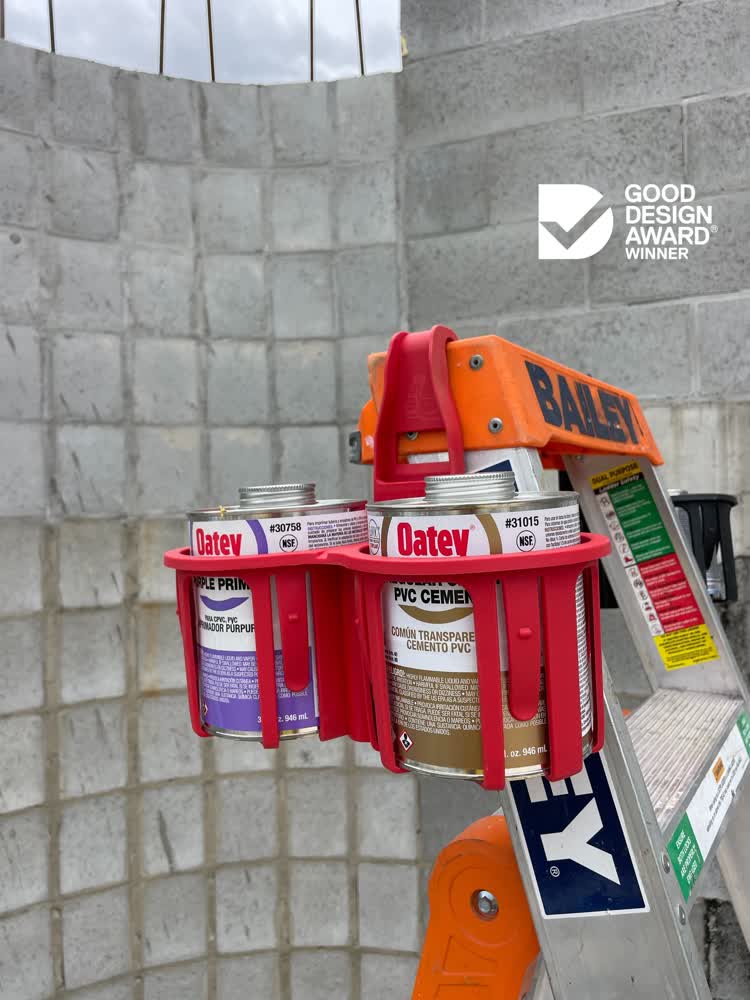 Red tool caddy holding Solvent cement cans against a concrete wall with Good Design Award logo.